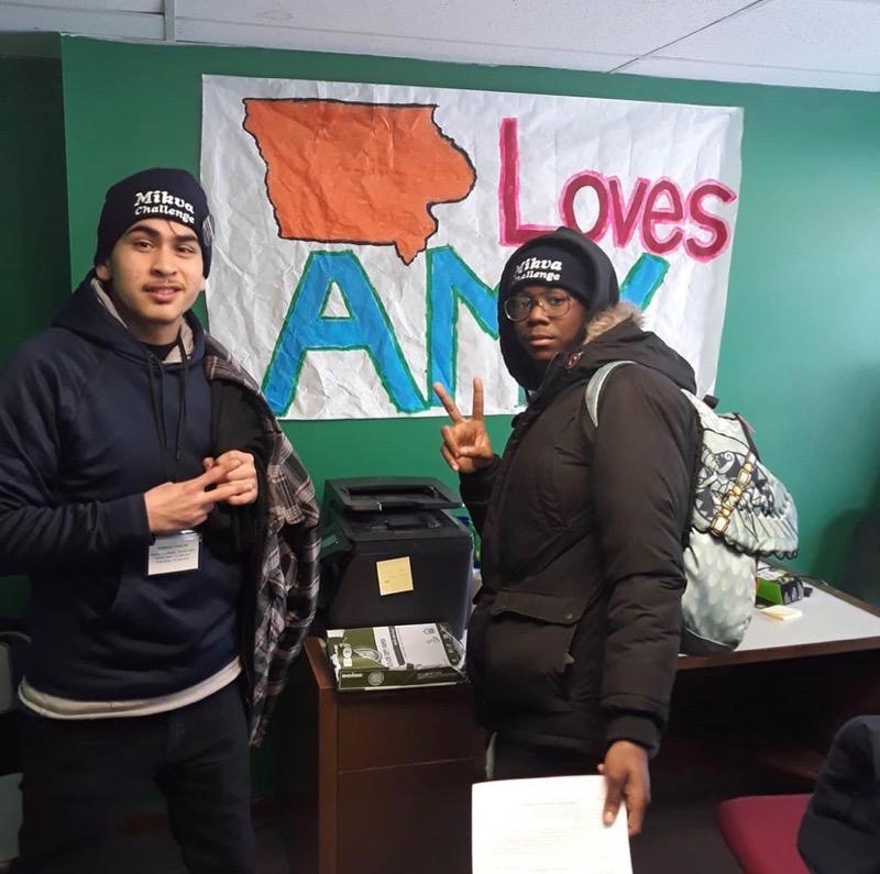 students stand in front of an Iowa loves Amy sign at the Caucus